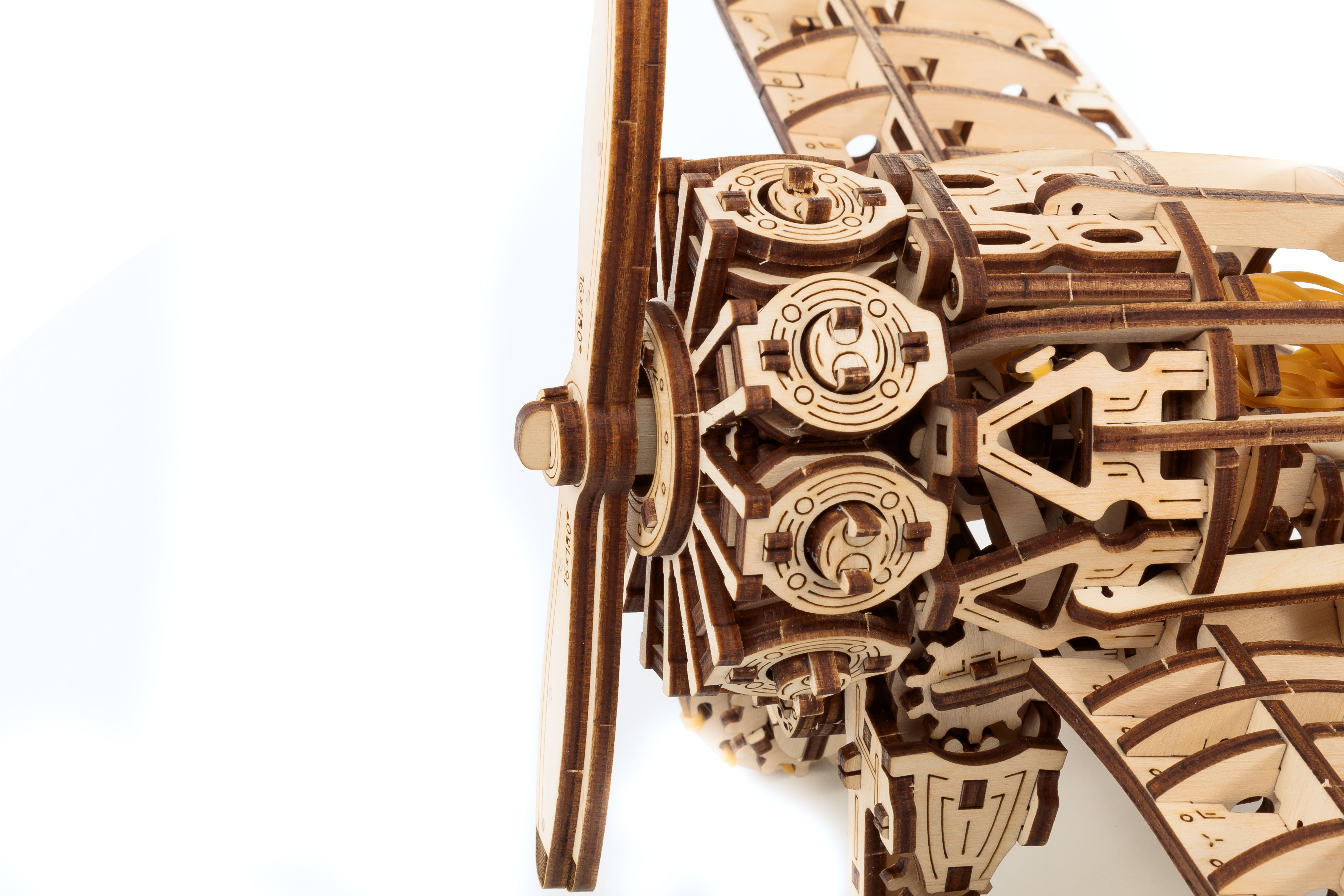 Nahaufnahme des 3D-Holzpuzzles „Flugzeug“, das die detaillierten Zahnräder und den Propeller vor einem weißen Hintergrund hervorhebt.