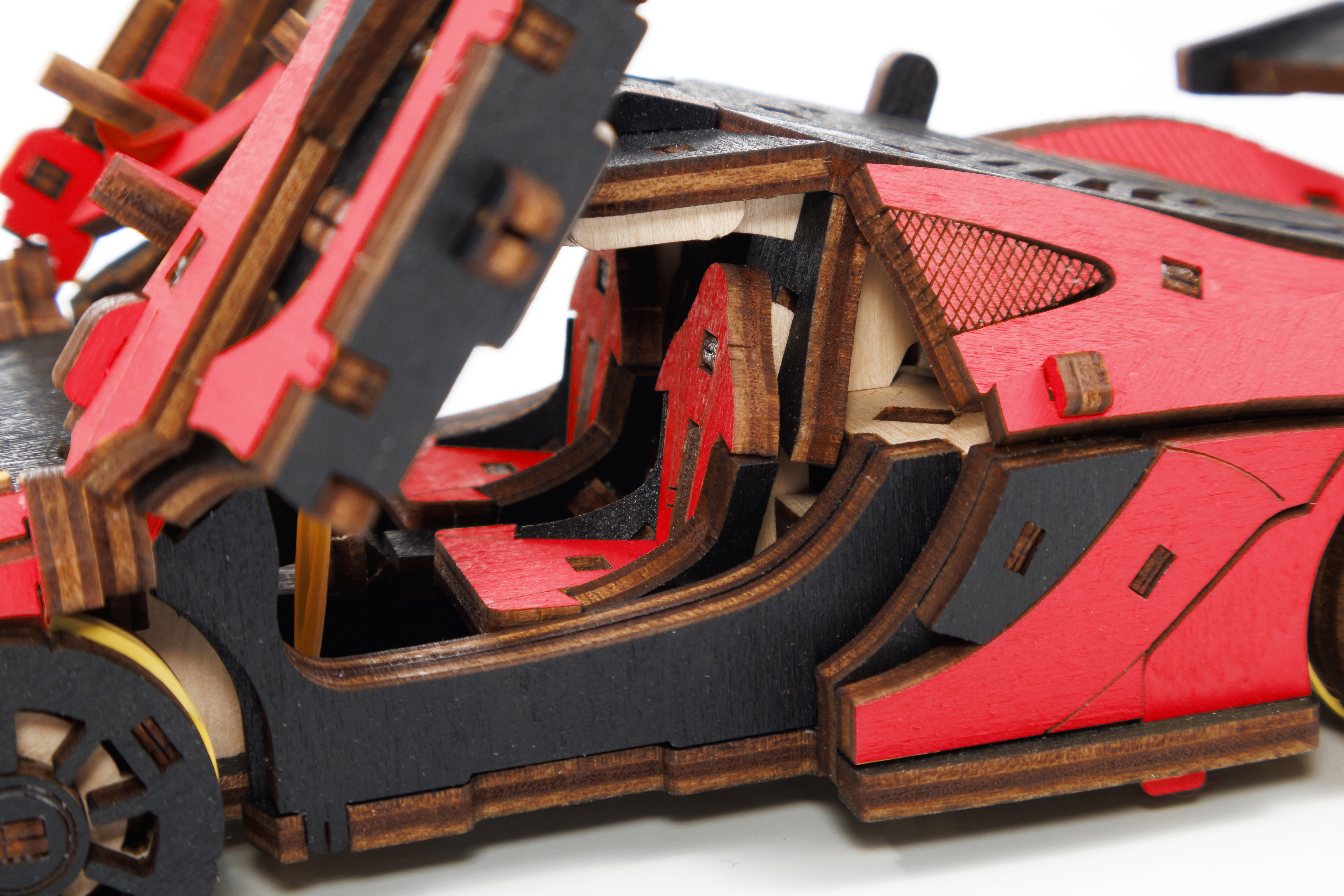 Nahaufnahme eines 3D-Holzpuzzles, Rennwagen rot mit roten und schwarzen Details und offenen Türen, die die Sitze zeigen – ideal für Modellbau-Fans und Rennsportbegeisterte.
