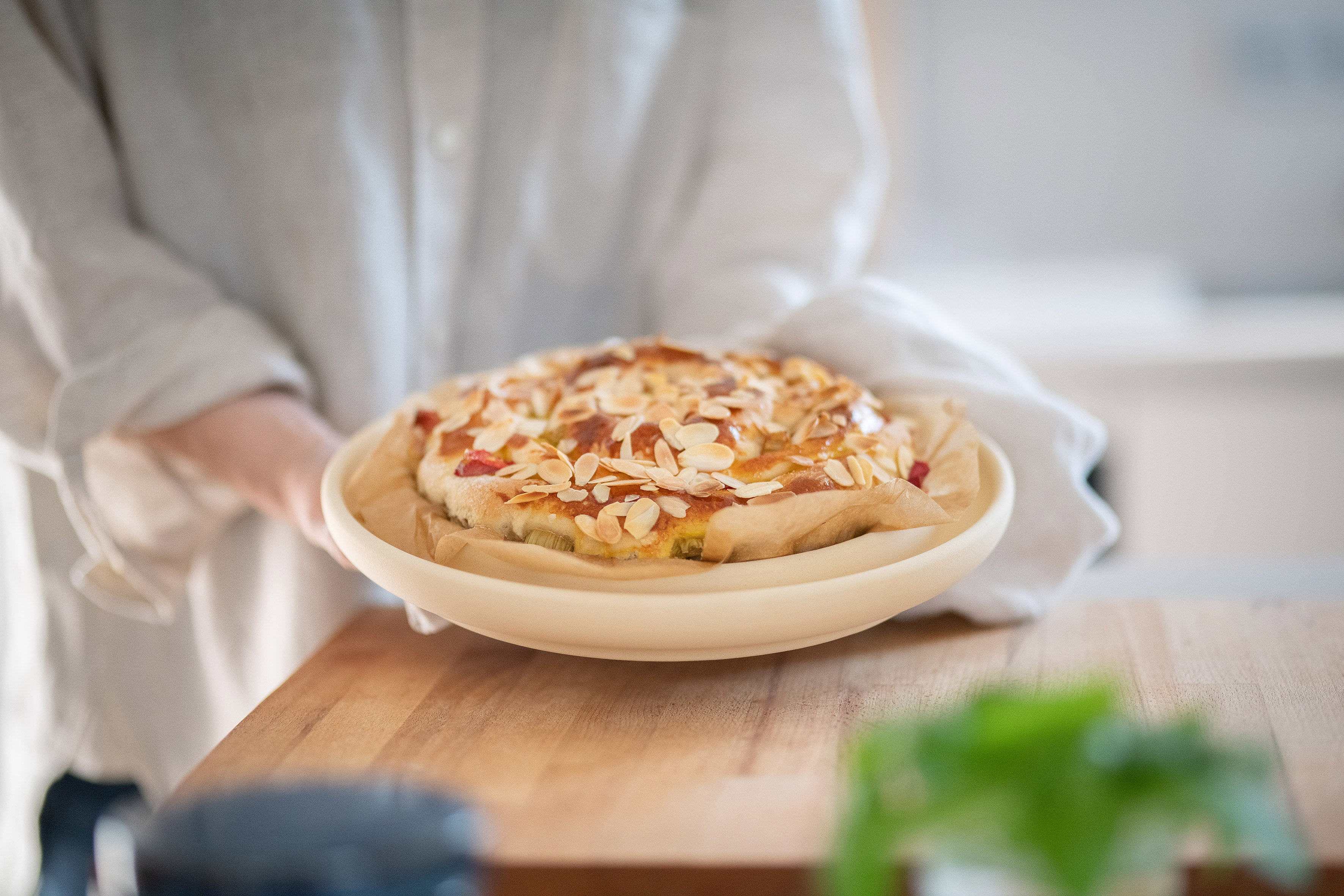 Die Backplatte Bread & Cake von DENK Keramik mit Mandelgebäck in den Händen einer Person