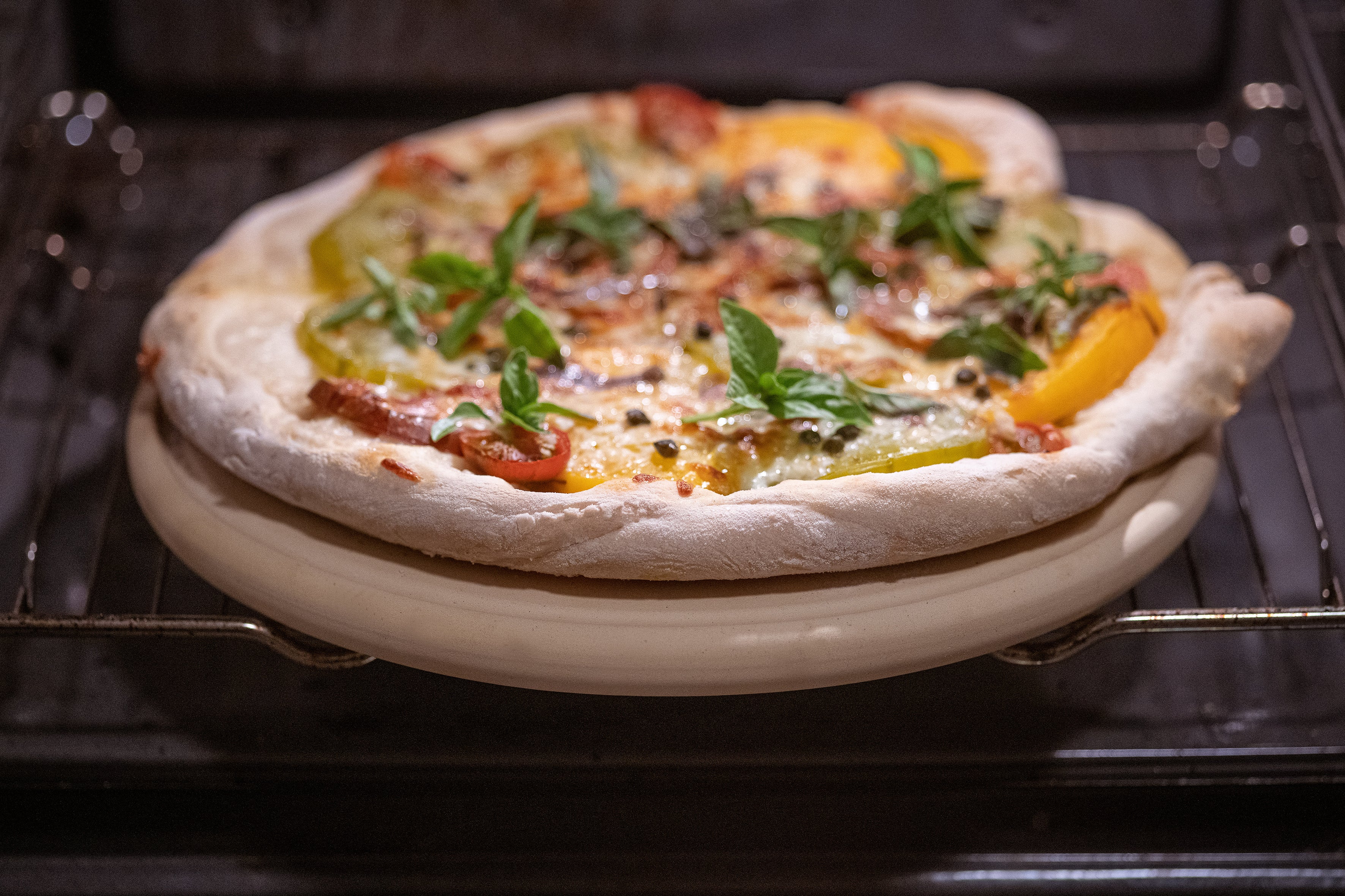 Die Pizzaplatte von DENK Keramik mit einer Pizza im Ofen