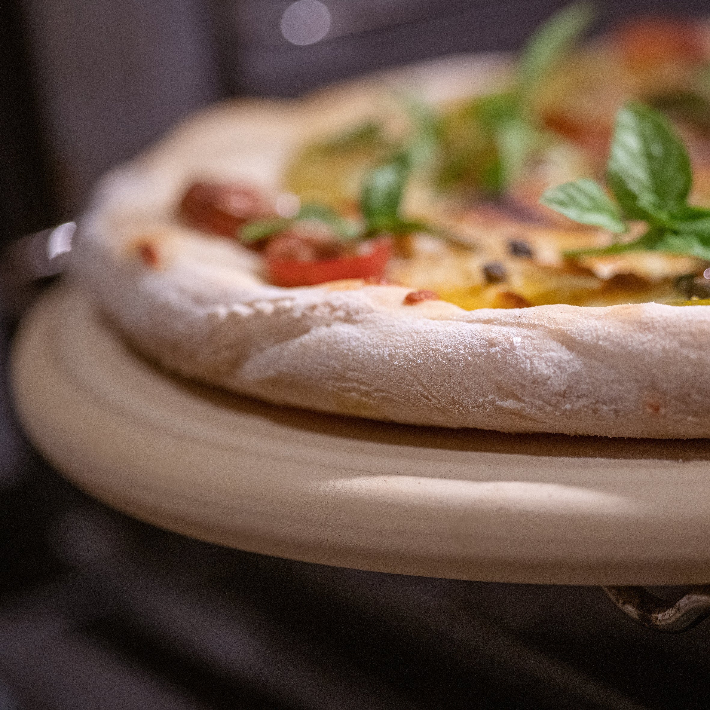 Nahaufnahme der Pizzaplatte von DENK Keramik mit einer Pizza im Ofen