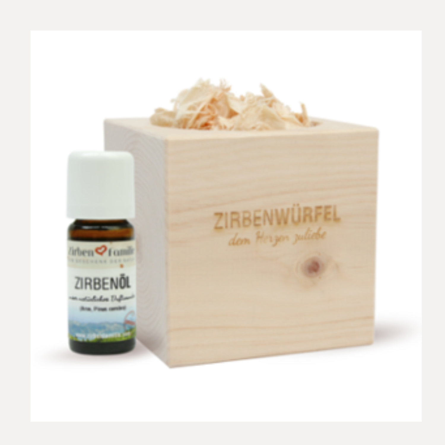 Neben dem ZirbenWürfel-Set steht eine Flasche ätherisches Öl, die mit duftenden Holzspänen gefüllt ist.