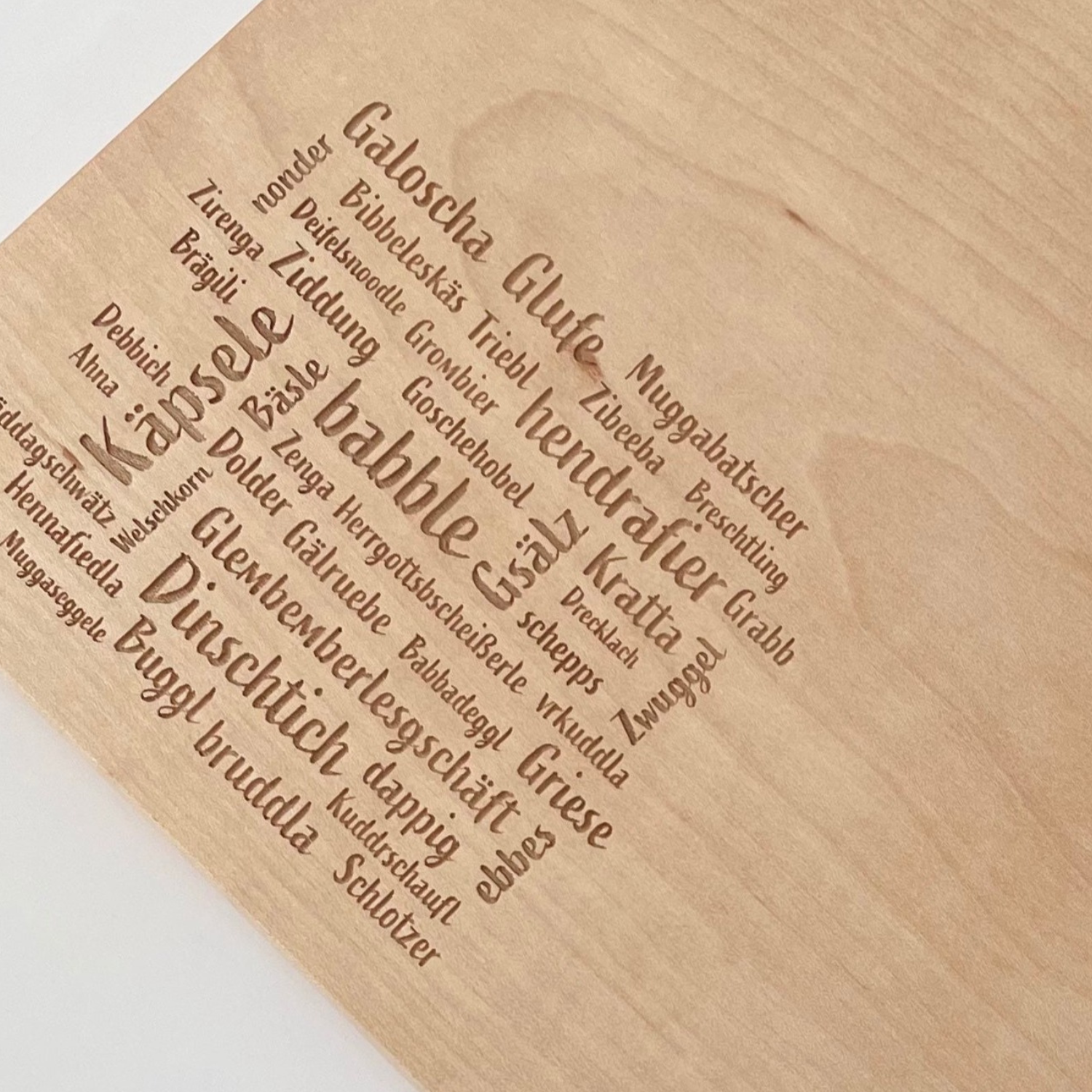 Das Mundart-Brettle ist ein Holzbrett, in das charmante deutsche Wörter und Sätze im bayerischen Dialekt eingraviert sind und das kunstvoll in der Form Bayerns angeordnet ist.