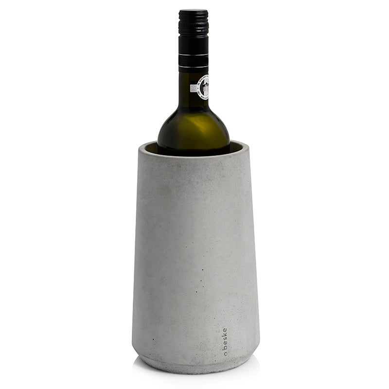 Eine Flasche Weißwein steht elegant auf weißem Hintergrund im hohen, zylindrischen Beske Weinkühler „Eiskar“, einem Weinkühler aus grauem Beton.
