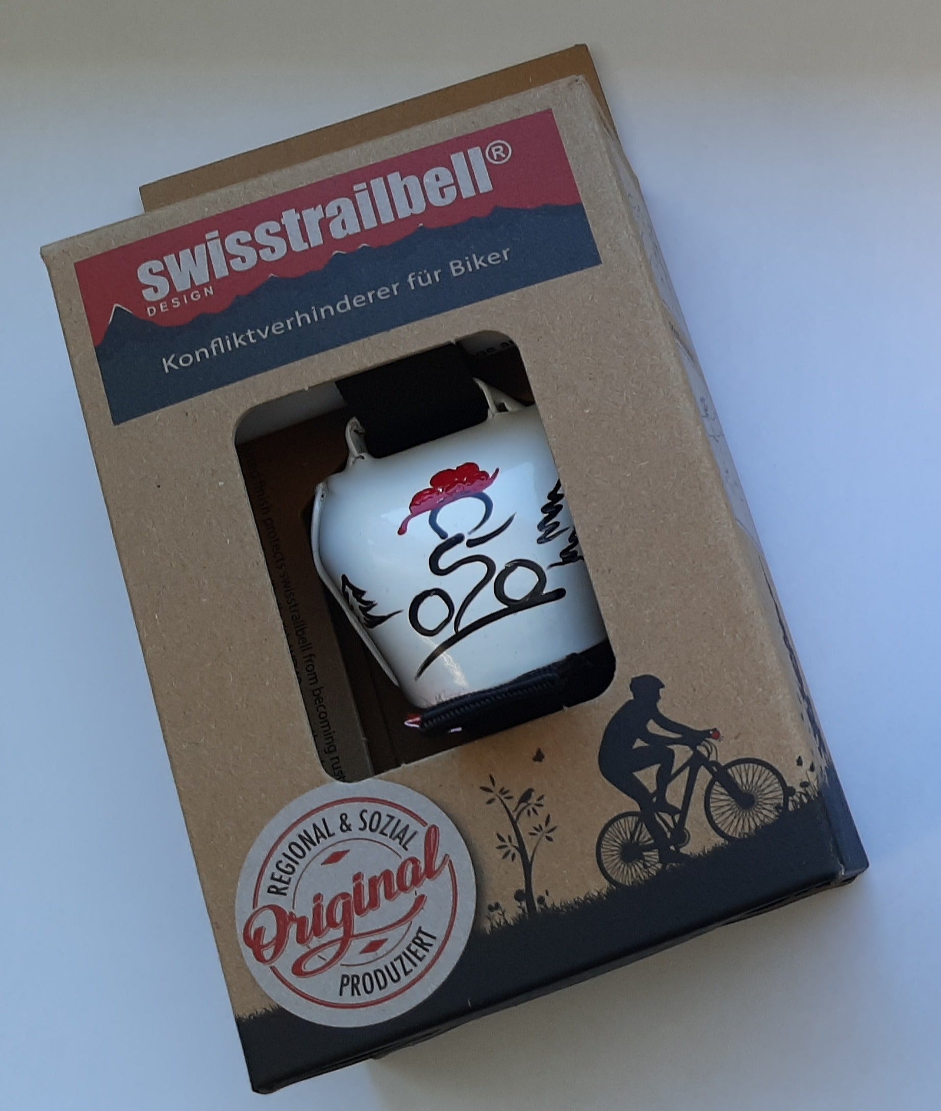 Die Fahrradglocke swisstrailbell® kommt in Verpackung mit Radfahrer-Motiv und „Original“-Plakette auf der Box.