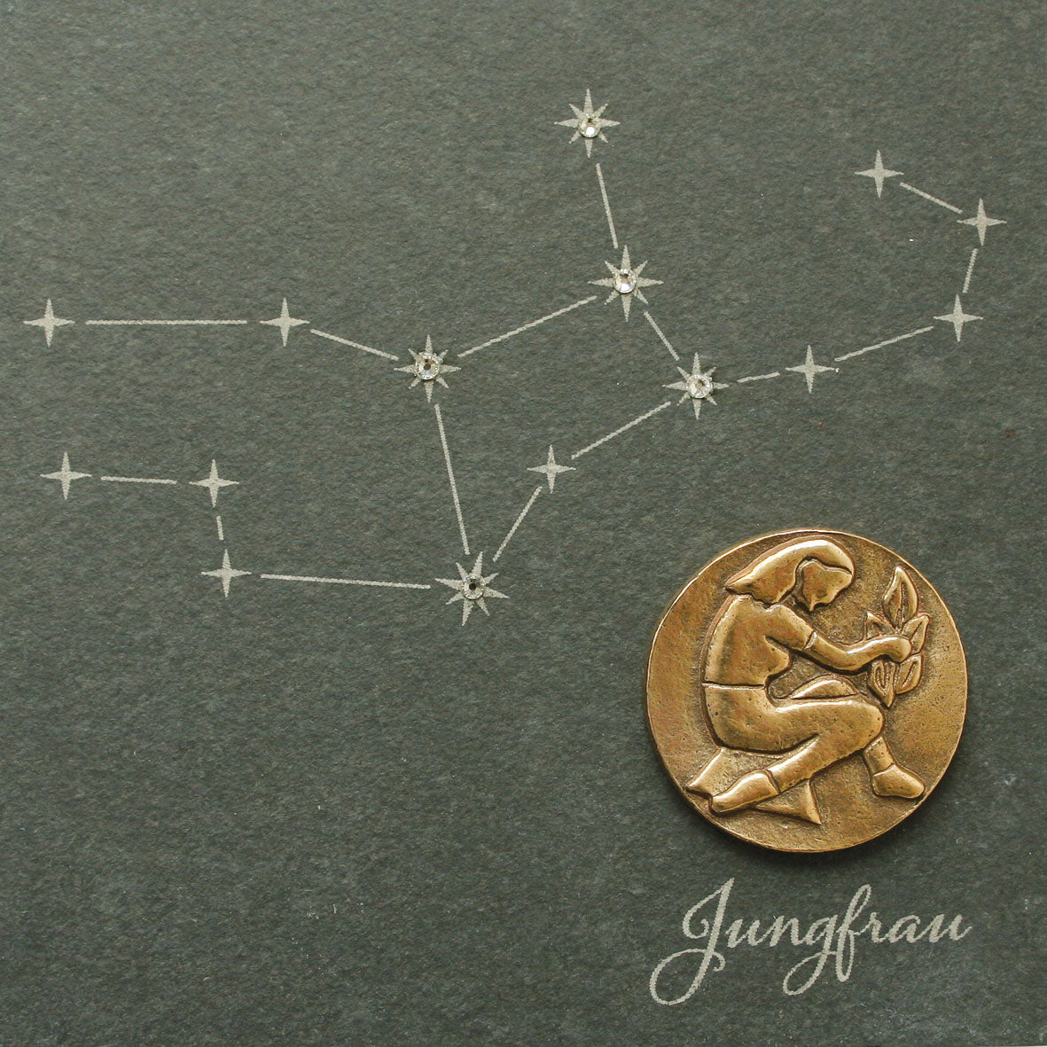 Eine Zeichnung des Sternbilds Jungfrau und eine Münze mit einer weiblichen Figur auf einem Naturschiefer mit der Aufschrift „Jungfrau“. Teil der Sammlung Bronze-Sternzeichen.