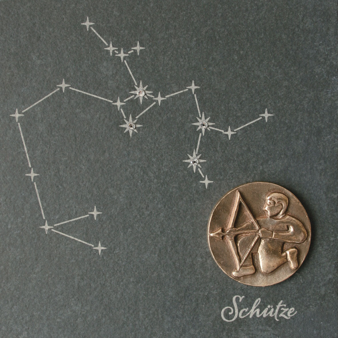 Bronze-Sternzeichen: Eine Zeichnung des Sternbilds Schütze mit einem Medaillon mit einem Bogenschützen aus Bronze-Sternzeichen, verziert mit Swarovski-Elementen und der eleganten Inschrift „Schütze“ darunter.