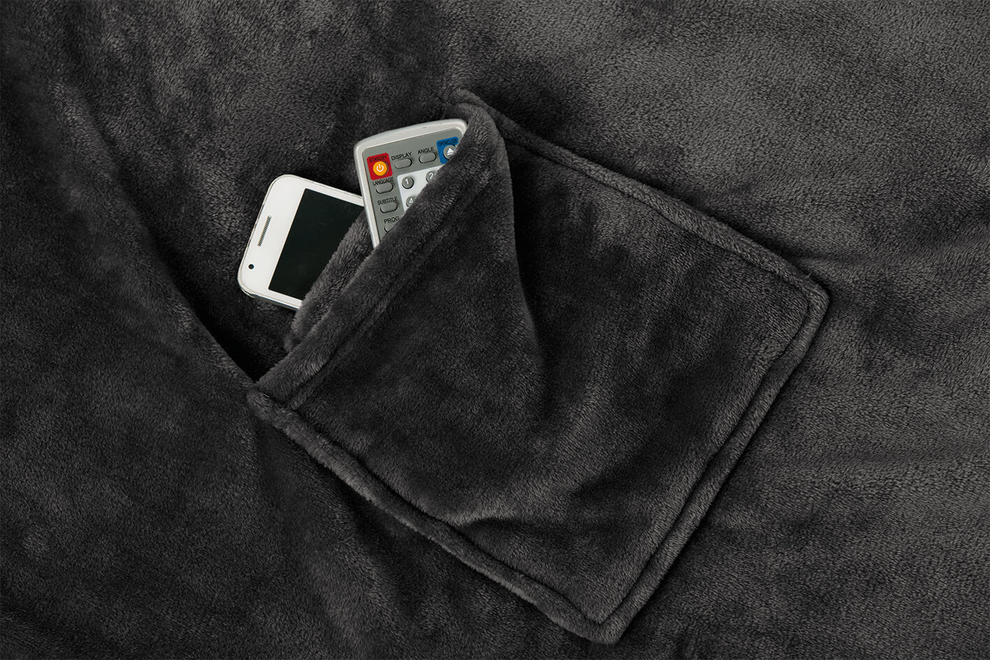 Ein Telefon und eine Fernbedienung befinden sich in der Tasche einer dunkelgrauen Ärmeldecke.