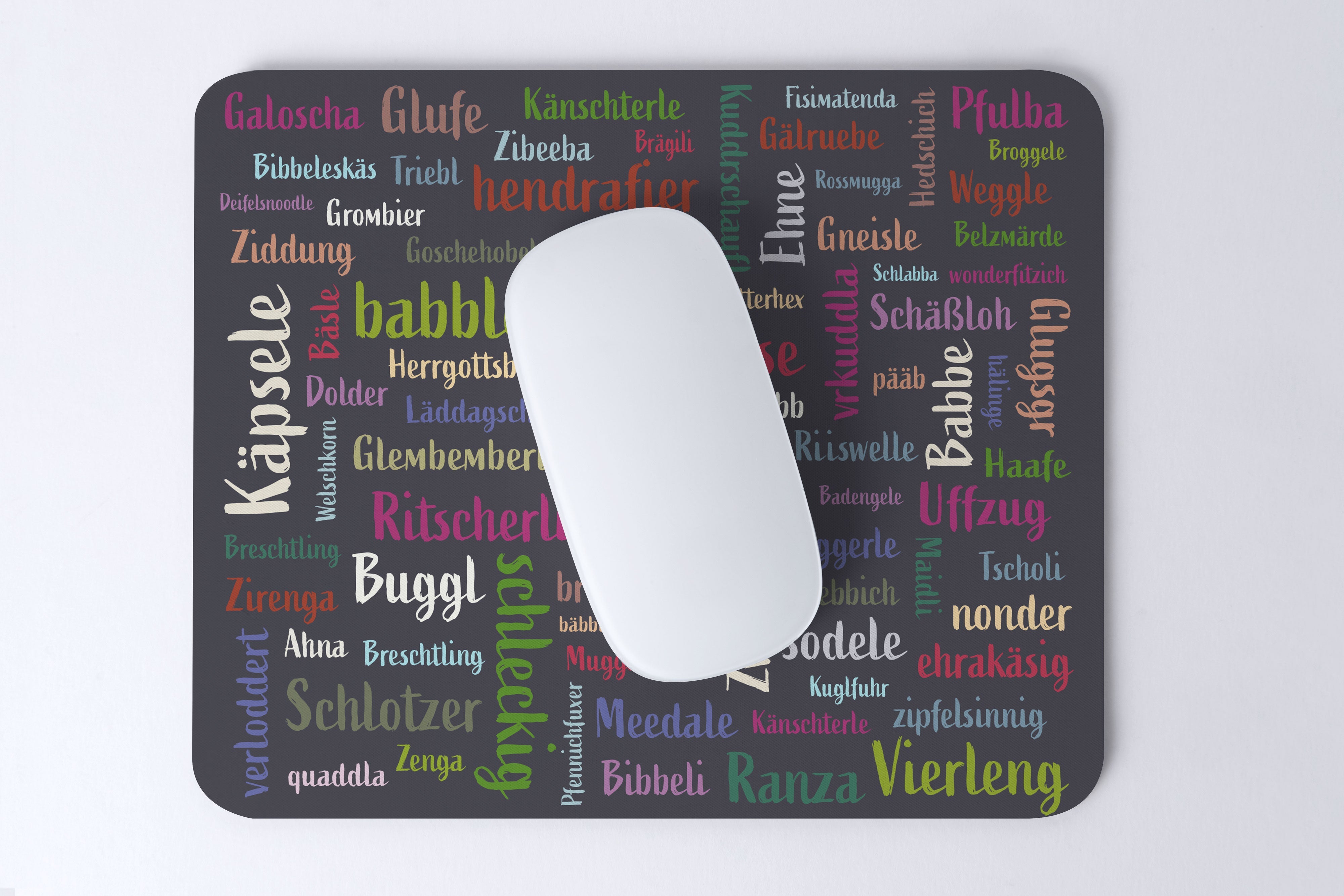 Das Mundart-Mousepad ist ein farbenfrohes Mauspad mit deutschen Wörtern in verschiedenen Schriftarten, das Oberflächenschutz und ein einzigartiges Mundart-Design für Ihre weiße Computermaus bietet.