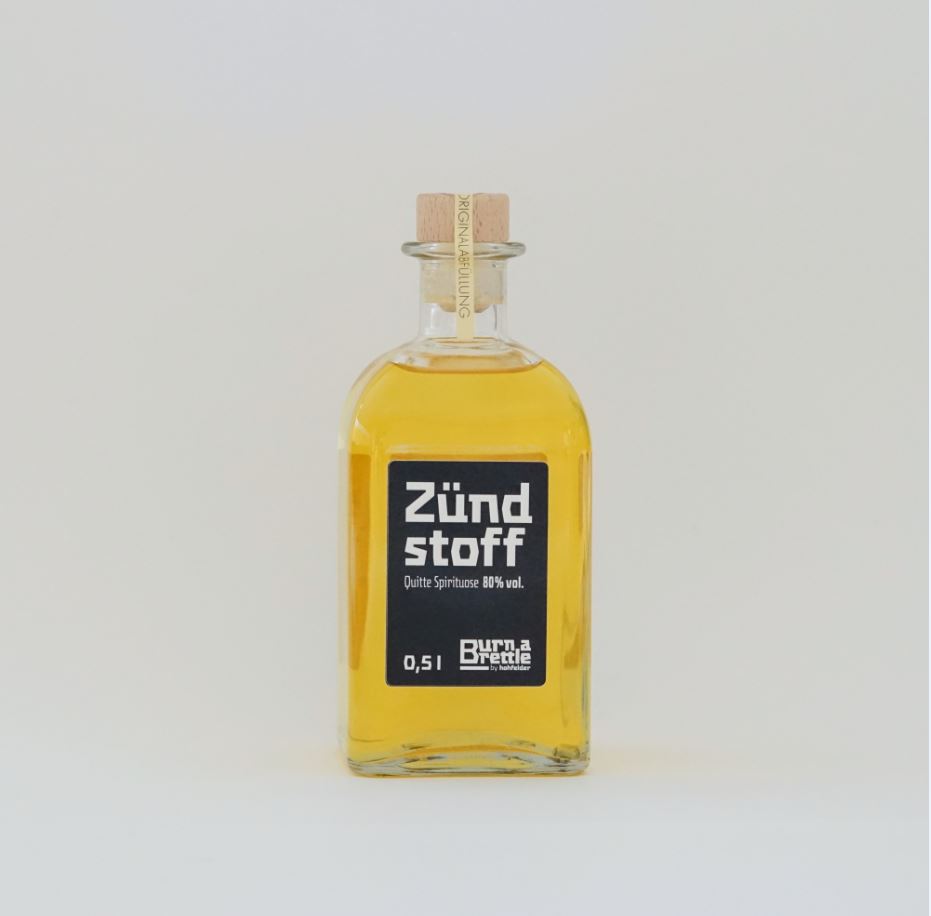 Eine klare Glasflasche, gefüllt mit einer gelben Flüssigkeit, mit der Aufschrift „Burn a Brettle Zündstoff“ und einem Korken verschlossen – ideal für alle, die auf der Suche nach einzigartigen Geschmackssorten sind.