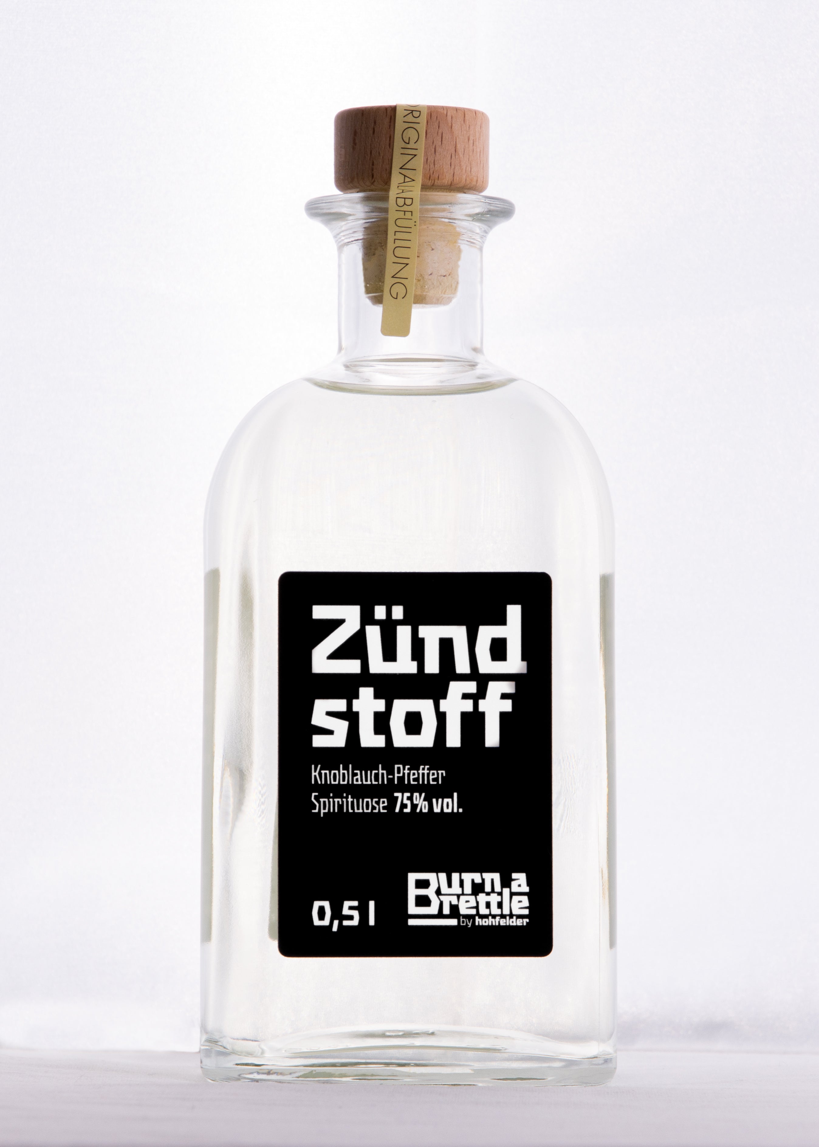 Burn a Brettle Zündstoff: Klare Glasflasche mit Holzkorken, Aufschrift „Zündstoff“, gefüllt mit 75 % vol. Knoblauch-Pfeffer-Spirit – ein feuriger Geschmack, der garantiert Ihre Sinne entzündet.