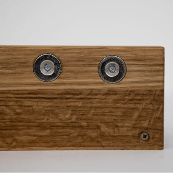 Nahaufnahme von zwei Metallbolzen und einer Schraube, die in hellem Holz befestigt sind, Teil eines magnetischen Schlüsselbretts.