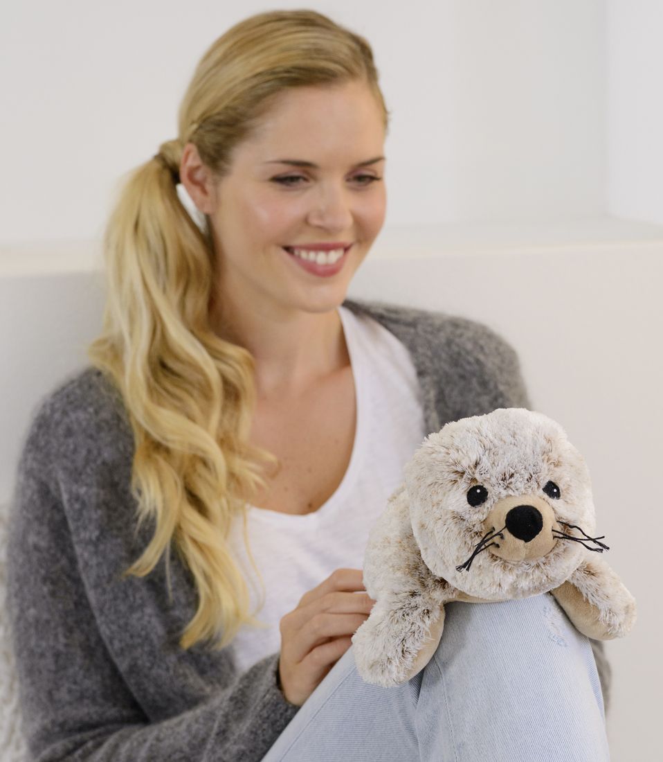 Frau mit Warmies Kuscheltier Robbe mit Wärmefunktion