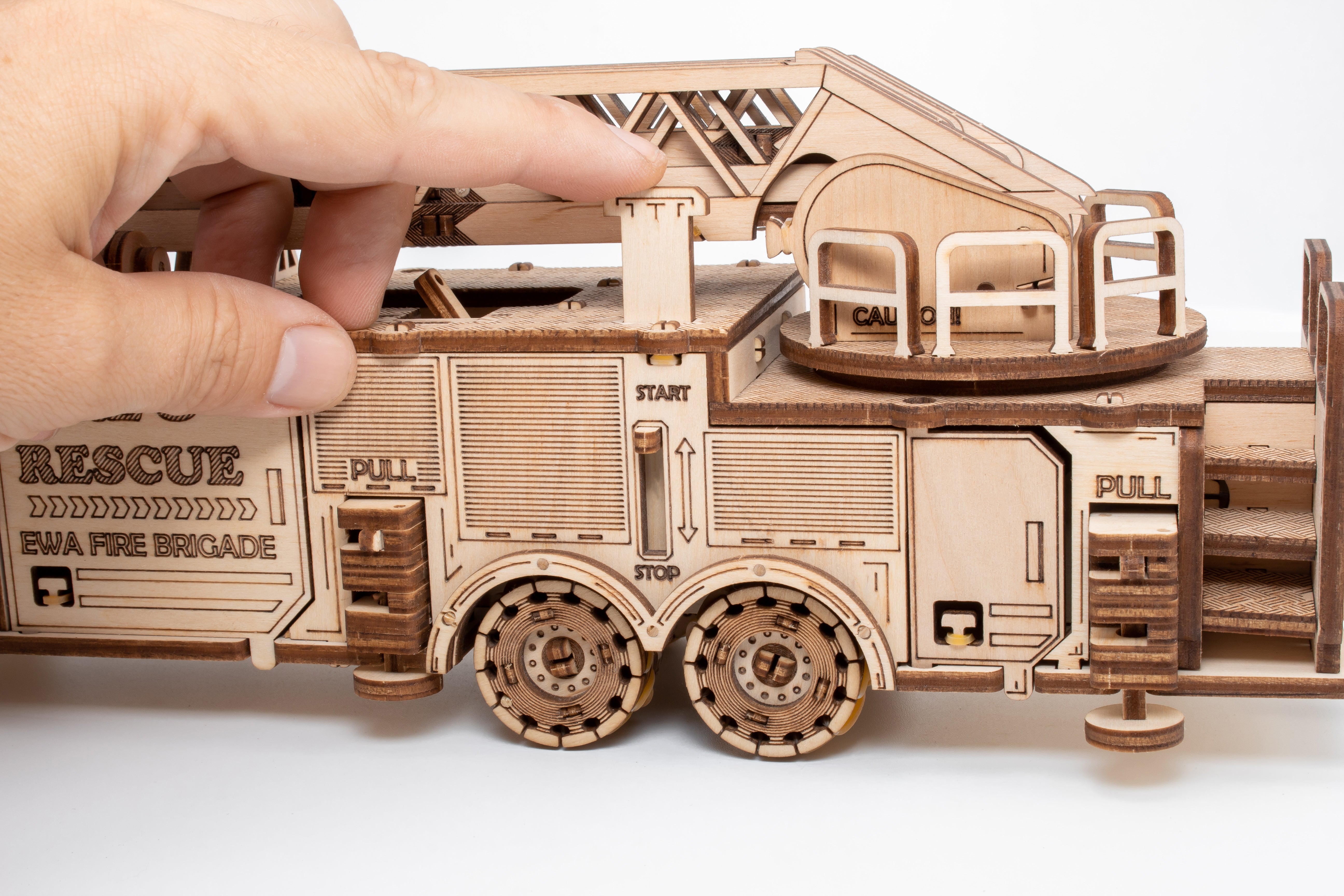 Eine Hand justiert das 3D-Holzpuzzle, Mechanisches Feuerwehrauto – gefertigt aus hochwertigem Holz mit lasergeschnittenen Details und beweglichen Teilen, die die Feinmotorik fördern.