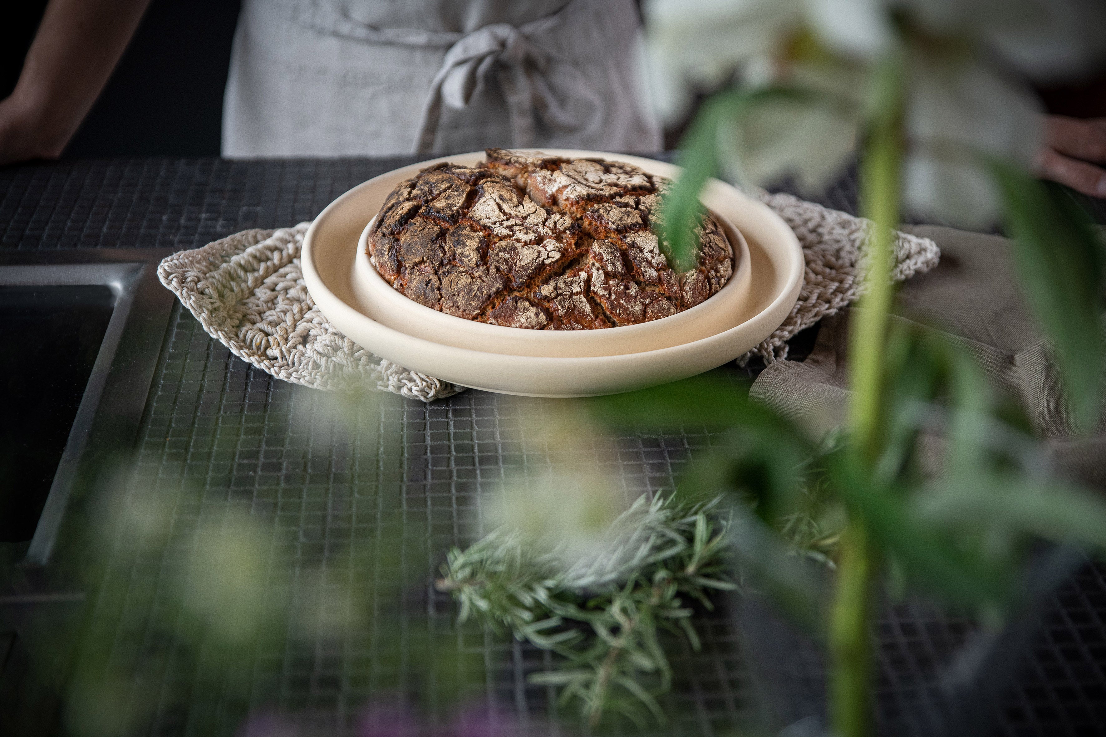 Die Backplatte Bread & Cake von DENK Keramik auf  dunkler Arbeitsplatte mit einem Brot