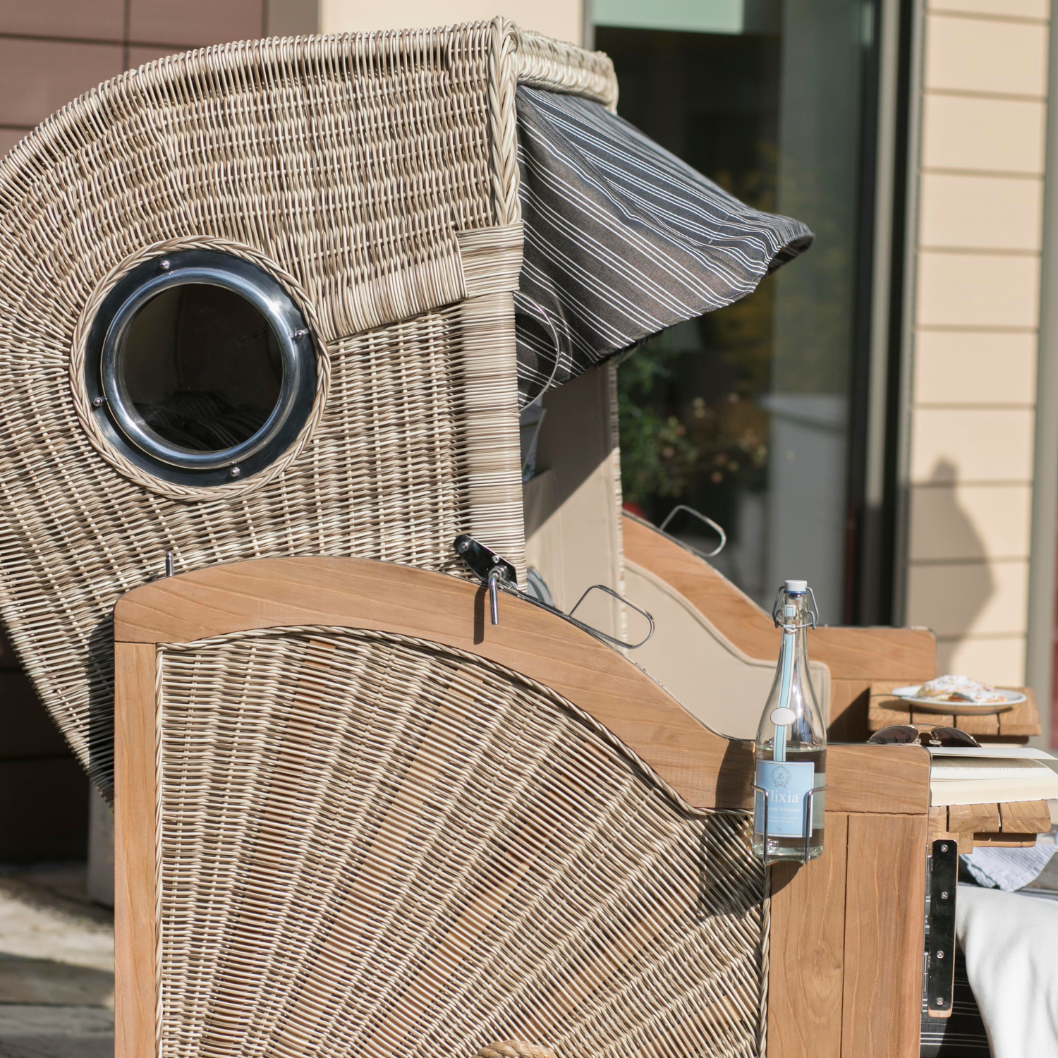 Der Strandkorb DÜNE Design grau mit Nadelstreifen, inkl. Gratis Feuerschale, bietet stilvolles Outdoor-Relaxen – ideal für Drinks, Snacks und Gemütlichkeit unter dem Dach.